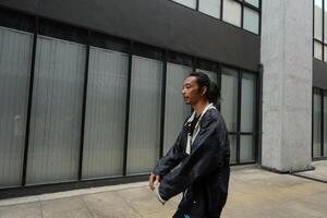 ASian man is dancing in hip hop style at outdoor space. Professional solo dancer is performing in public area. photo