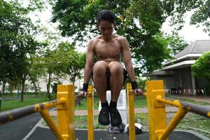 Asian man practicing gymnastics, doing gymnastics bar and hoop exercises and stretching, resting for sports. photo