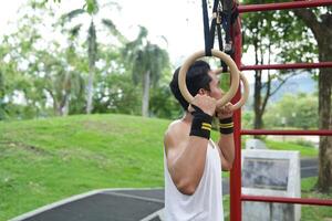 Asian man practicing gymnastics, doing gymnastics bar and hoop exercises and stretching, resting for sports. photo