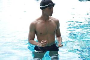 Asian men practicing swimming and preparing to play water polo and stretching and resting for water sports. photo