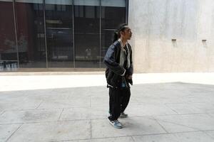 ASian man is dancing in hip hop style at outdoor space. Professional solo dancer is performing in public area. photo