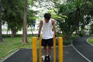 Asian man practicing gymnastics, doing gymnastics bar and hoop exercises and stretching, resting for sports. photo