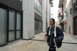 ASian man is dancing in hip hop style at outdoor space. Professional solo dancer is performing in public area. photo