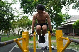 Asian man practicing gymnastics, doing gymnastics bar and hoop exercises and stretching, resting for sports. photo