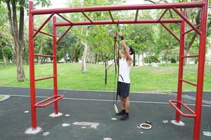 Asian man practicing gymnastics doing gymnastics bar and hoop exercises and stretching and resting for sports. photo