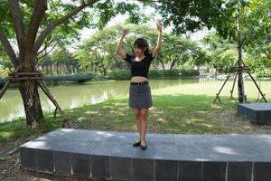 Asian woman dancing in the middle of a park photo