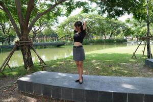 Asian woman dancing in the middle of a park photo