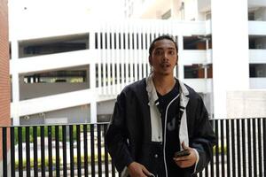 ASian man is dancing in hip hop style at outdoor space. Professional solo dancer is performing in public area. photo