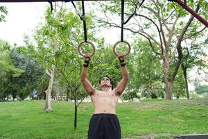 Asian man practicing gymnastics, doing gymnastics bar and hoop exercises and stretching, resting for sports. photo