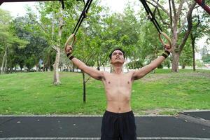 Asian man practicing gymnastics, doing gymnastics bar and hoop exercises and stretching, resting for sports. photo