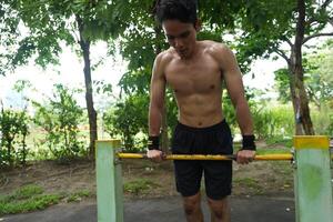 Asian man practicing gymnastics, doing gymnastics bar and hoop exercises and stretching, resting for sports. photo