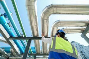 Industrial engineer adjusting pipeline valve with radio communication on construction site. Engineer on urban construction site using radio to coordinate with team on a sunny industrial rooftop. photo
