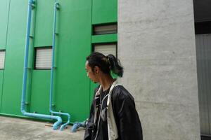 ASian man is dancing in hip hop style at outdoor space. Professional solo dancer is performing in public area. photo