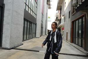 ASian man is dancing in hip hop style at outdoor space. Professional solo dancer is performing in public area. photo