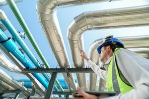Industrial engineer adjusting pipeline valve with radio communication on construction site. Engineer on urban construction site using radio to coordinate with team on a sunny industrial rooftop. photo