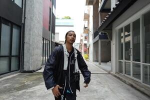 ASian man is dancing in hip hop style at outdoor space. Professional solo dancer is performing in public area. photo