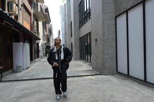 ASian man is dancing in hip hop style at outdoor space. Professional solo dancer is performing in public area. photo