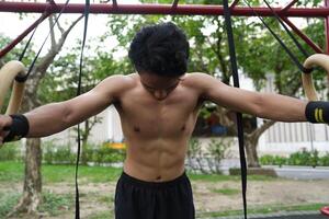 Asian man practicing gymnastics, doing gymnastics bar and hoop exercises and stretching, resting for sports. photo