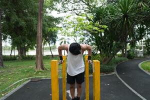 Asian man practicing gymnastics, doing gymnastics bar and hoop exercises and stretching, resting for sports. photo