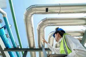 Industrial engineer adjusting pipeline valve with radio communication on construction site. Engineer on urban construction site using radio to coordinate with team on a sunny industrial rooftop. photo