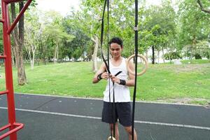 Asian man practicing gymnastics doing gymnastics bar and hoop exercises and stretching and resting for sports. photo