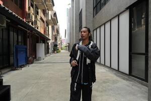 ASian man is dancing in hip hop style at outdoor space. Professional solo dancer is performing in public area. photo