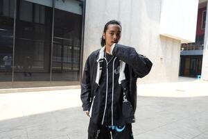 ASian man is dancing in hip hop style at outdoor space. Professional solo dancer is performing in public area. photo