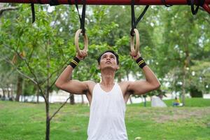 Asian man practicing gymnastics doing gymnastics bar and hoop exercises and stretching and resting for sports. photo