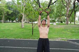 Asian man practicing gymnastics, doing gymnastics bar and hoop exercises and stretching, resting for sports. photo