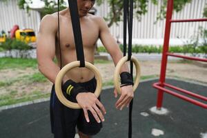 Asian man practicing gymnastics, doing gymnastics bar and hoop exercises and stretching, resting for sports. photo