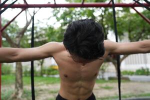 Asian man practicing gymnastics, doing gymnastics bar and hoop exercises and stretching, resting for sports. photo