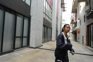 ASian man is dancing in hip hop style at outdoor space. Professional solo dancer is performing in public area. photo