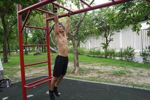 Asian man practicing gymnastics, doing gymnastics bar and hoop exercises and stretching, resting for sports. photo