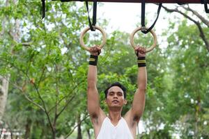 Asian man practicing gymnastics doing gymnastics bar and hoop exercises and stretching and resting for sports. photo
