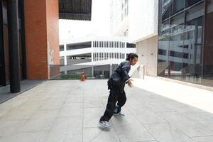 ASian man is dancing in hip hop style at outdoor space. Professional solo dancer is performing in public area. photo