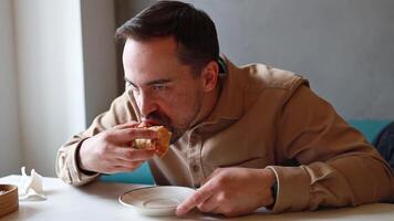 A man eats a triangular pie, samsa or echpochmak in a cafe video