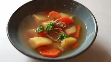 Close-up of meat soup with potatoes and carrots and herbs in a plate video