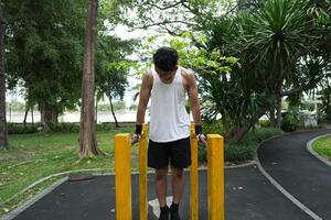 Asian man practicing gymnastics, doing gymnastics bar and hoop exercises and stretching, resting for sports. photo