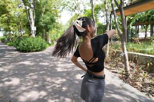 Asian woman dancing in the middle of a park photo