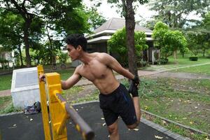Asian man practicing gymnastics, doing gymnastics bar and hoop exercises and stretching, resting for sports. photo