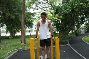Asian man practicing gymnastics, doing gymnastics bar and hoop exercises and stretching, resting for sports. photo