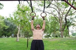 Asian man practicing gymnastics, doing gymnastics bar and hoop exercises and stretching, resting for sports. photo