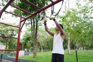 Asian man practicing gymnastics, doing gymnastics bar and hoop exercises and stretching, resting for sports. photo