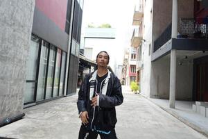 ASian man is dancing in hip hop style at outdoor space. Professional solo dancer is performing in public area. photo
