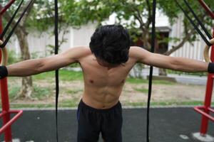 Asian man practicing gymnastics, doing gymnastics bar and hoop exercises and stretching, resting for sports. photo