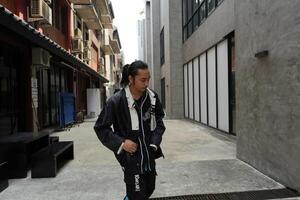 ASian man is dancing in hip hop style at outdoor space. Professional solo dancer is performing in public area. photo