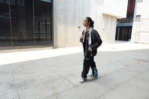 ASian man is dancing in hip hop style at outdoor space. Professional solo dancer is performing in public area. photo