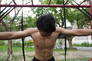Asian man practicing gymnastics, doing gymnastics bar and hoop exercises and stretching, resting for sports. photo