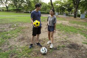 Asian man and woman are kicking and warming up before playing in soccer at outdoor park. photo