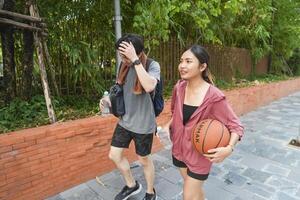 The male and female basketball players practice using the ball in the park court diligently and happily. photo